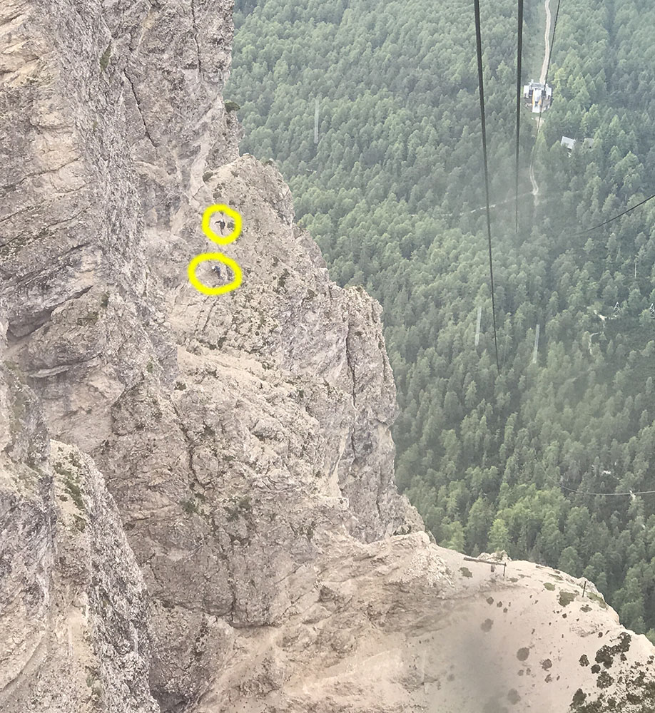 Two climbers, ringed in yellow, approach the sci club's headwall, as seen from the cable car.